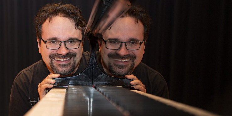 9.4.2026 Latvoissa Soi: Tuomas Turriago Tuomas Turriago katsoo kohti ja hänen kasvonsa heijastuvat pianosta.